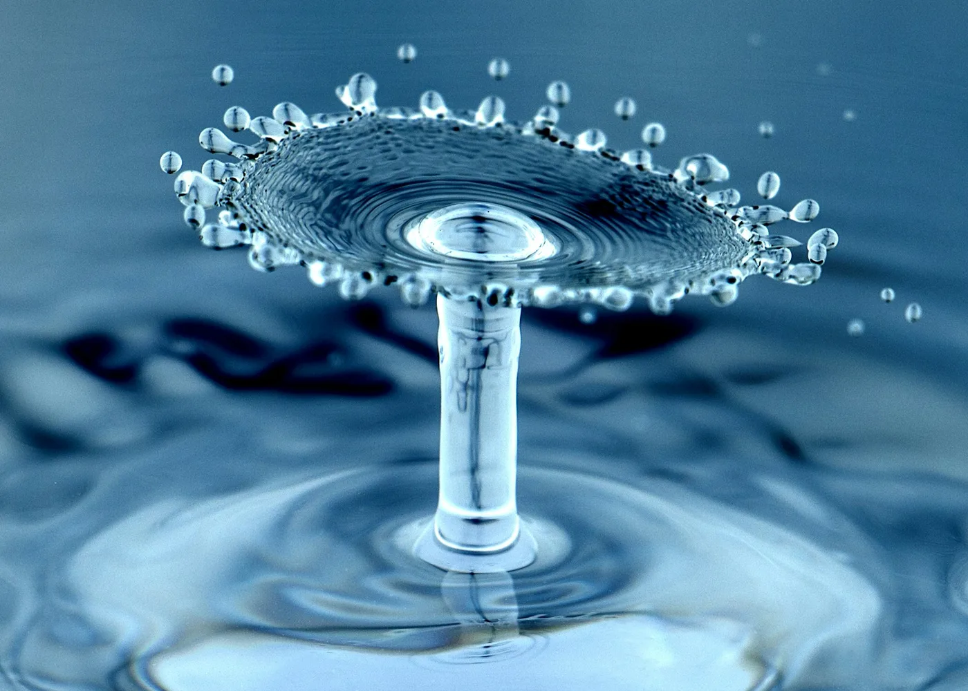 Macro water droplets suspended above a blue water surface